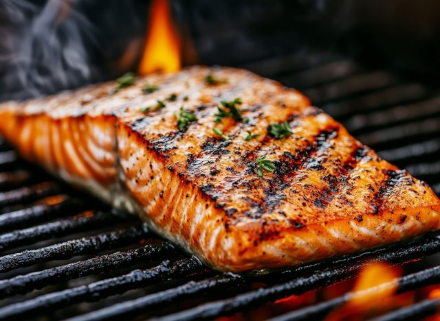 A close-up shot of a grilled salmon fillet on a hot BBQ grill. The fish is seasoned and cooked to perfection, with a crispy skin and juicy flesh. For your background business, poster, wallpaper
