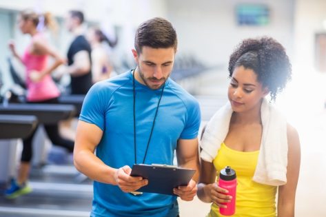 Fit woman talking to her trainer at the gym.