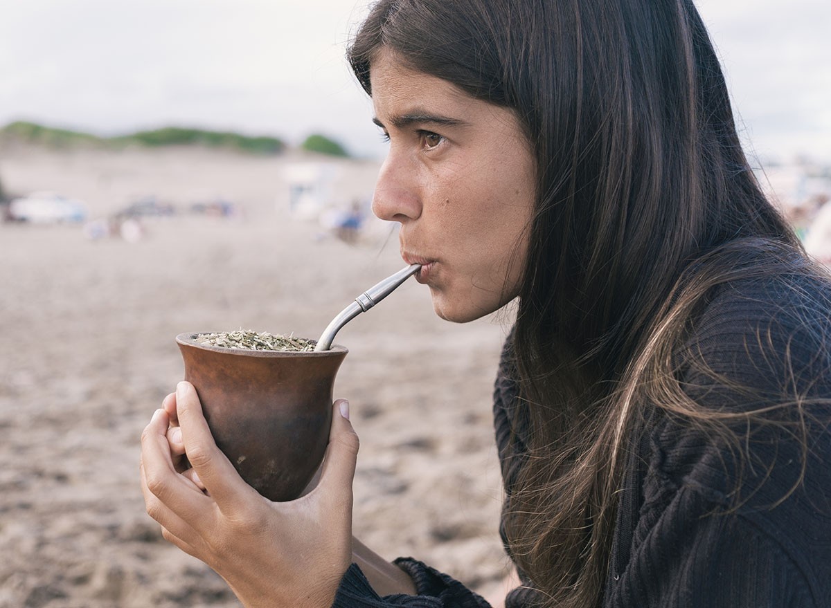 Young woman drinking traditional Argentinian yerba mate at the beach.
