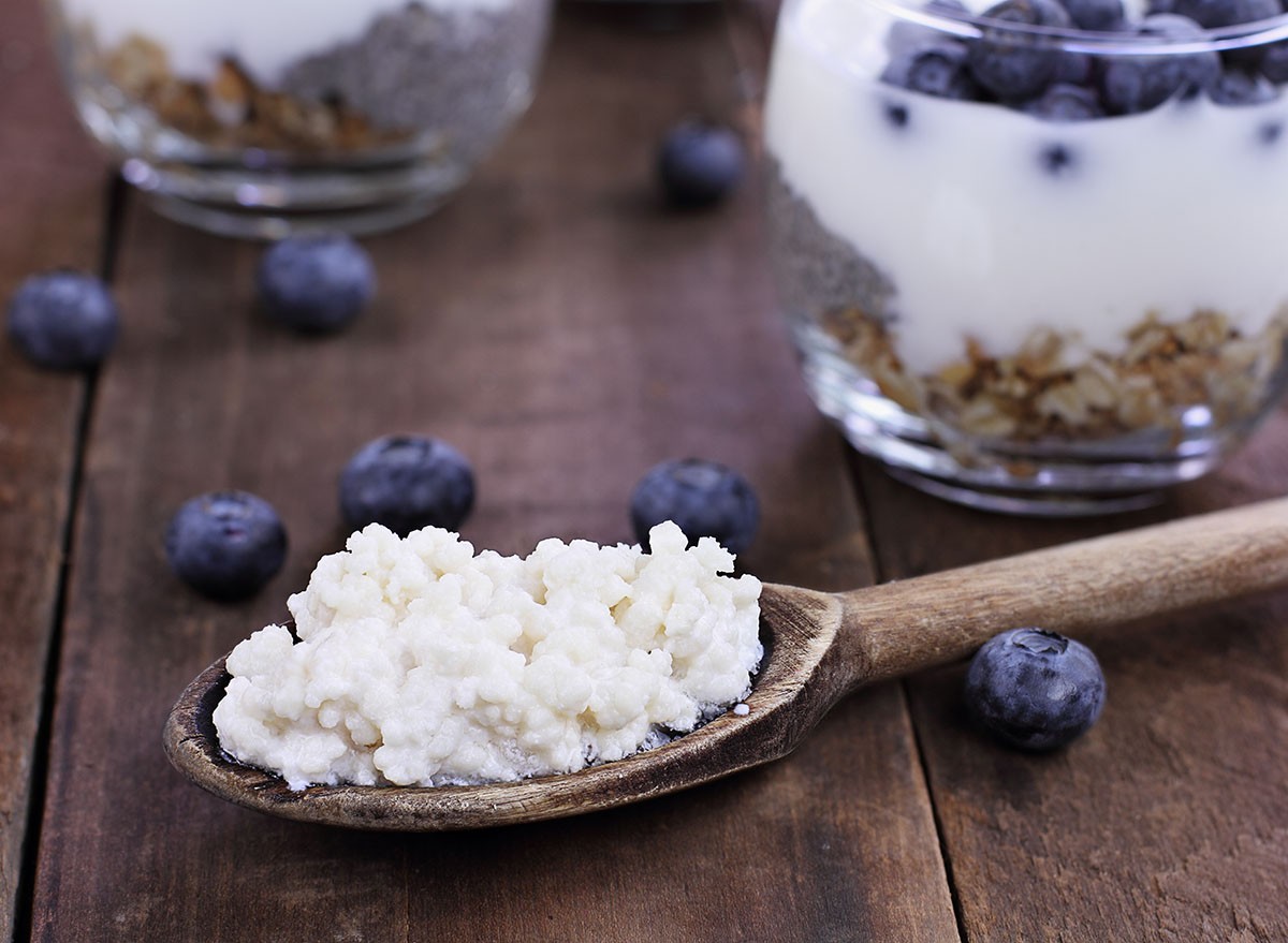 Kefir grains in wooden spoon in front of cups of Kefir Yogurt Parfaits. Kefir is one of the top health foods available providing powerful probiotics.