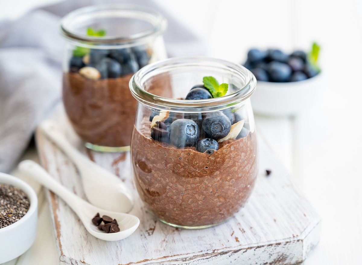 Chocolate chia pudding with blueberry, almonds and mint on top in a glass jar on a white wooden background. Healthy food. Copy space