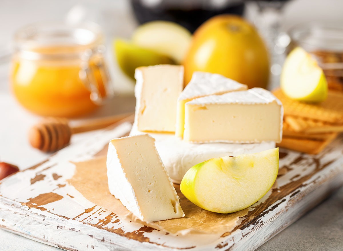 Camembert cheese. Fresh Brie cheese and a slice on a wooden board with nuts, honey and apples. Italian, French cheese. Selective focus