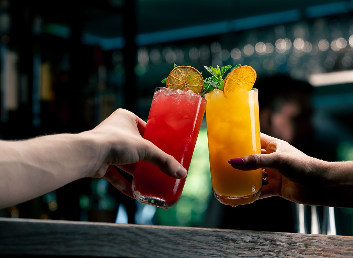 Close up of two people cheering cocktails in bar or disco club drinks and cocktails concept, alcohol