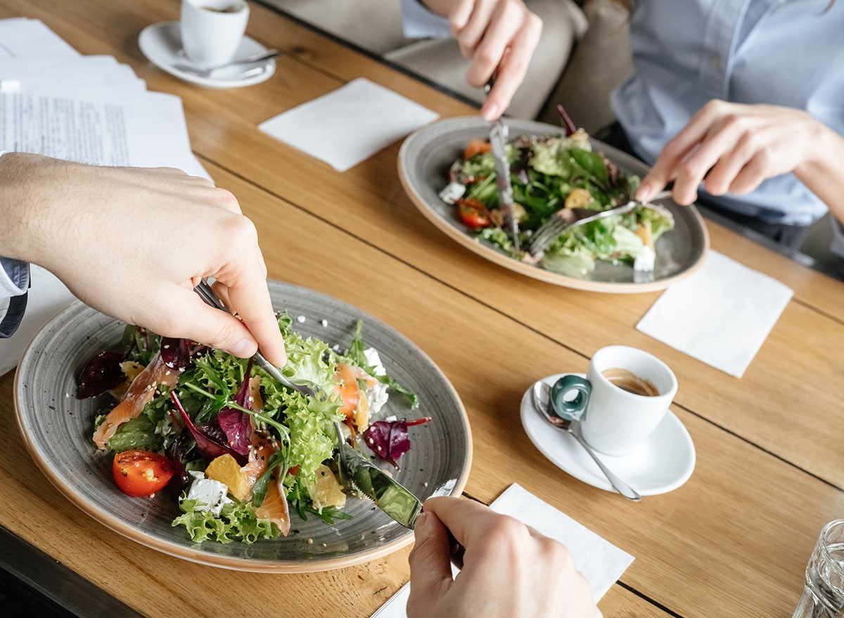 Man and woman having business lunch at restaurant sitting at table eating two plates of fresh vegetable salad close-up, lunch, salad, cafe, restaurant