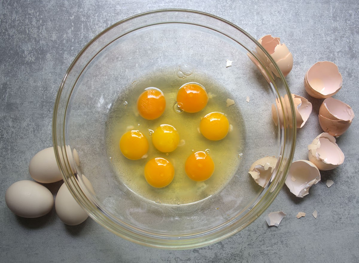 Raw eggs in glass bowl on kitchen table. Preparation of omelet