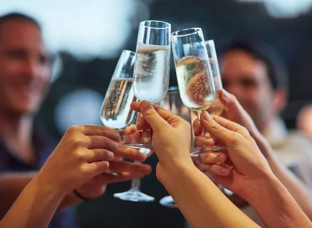 Bubbles, hands and toast with friends outdoor for celebration or social gathering together. Alcohol glass, champagne and cheers with group of people in backyard for milestone or new years for fun