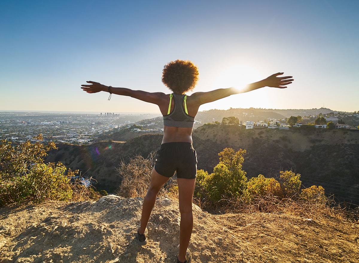 athletic african american woman celebrating reaching top of runyon canyon with arms open, hike, run, walk, incline
