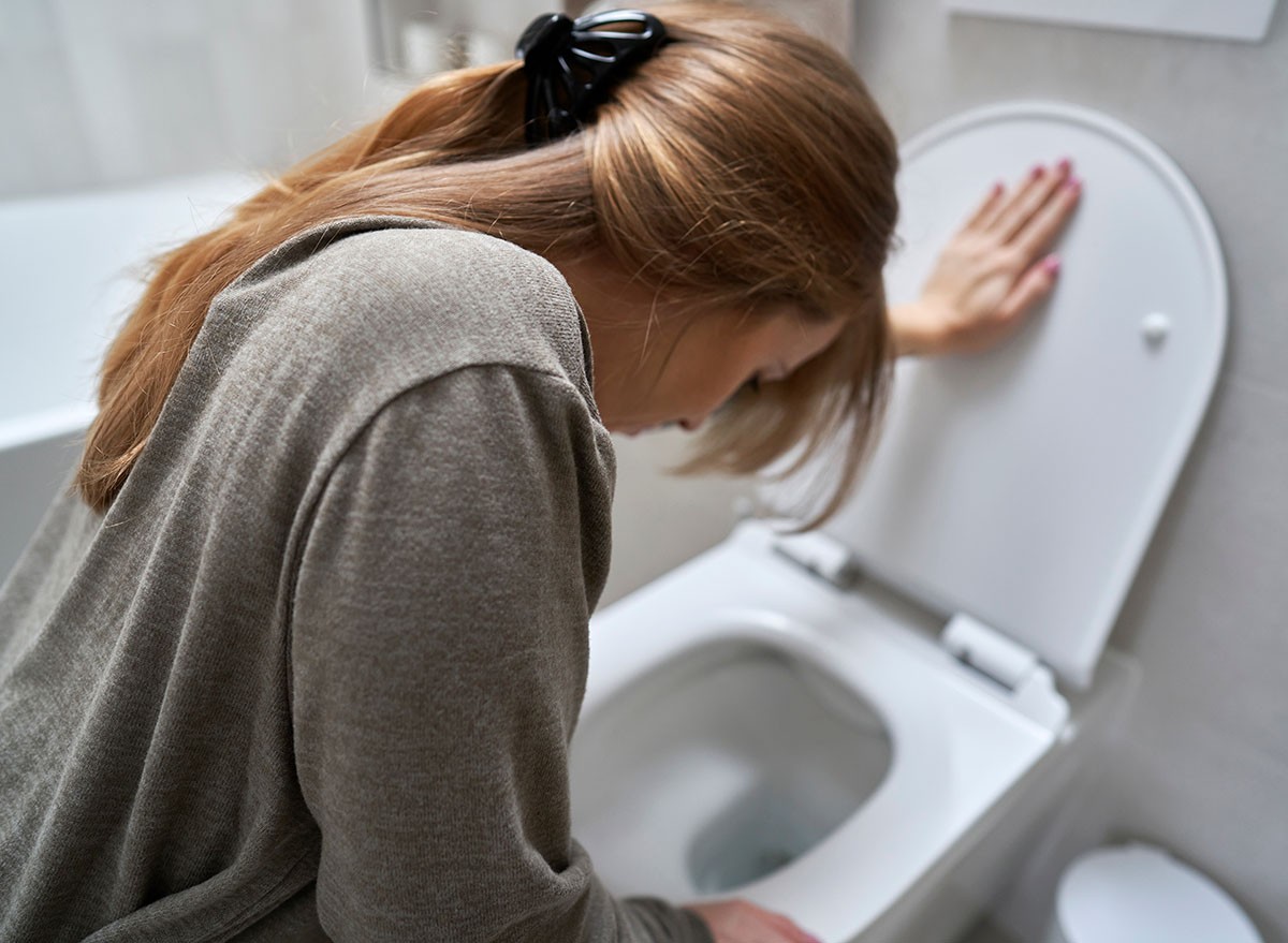 Woman bending over toilet and having a nausea, vomit, vomitting, sick, bathroom