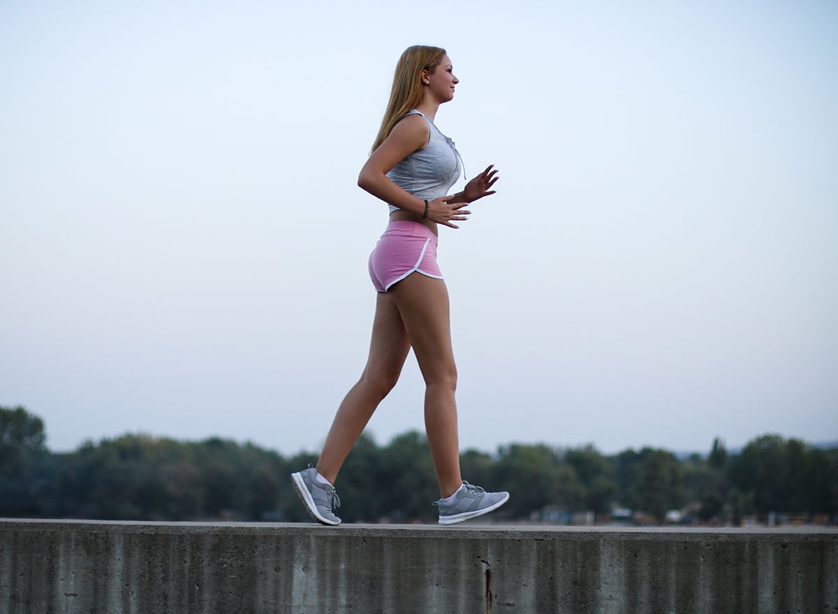 Young sportswoman brisk walking outdoors, urban style.