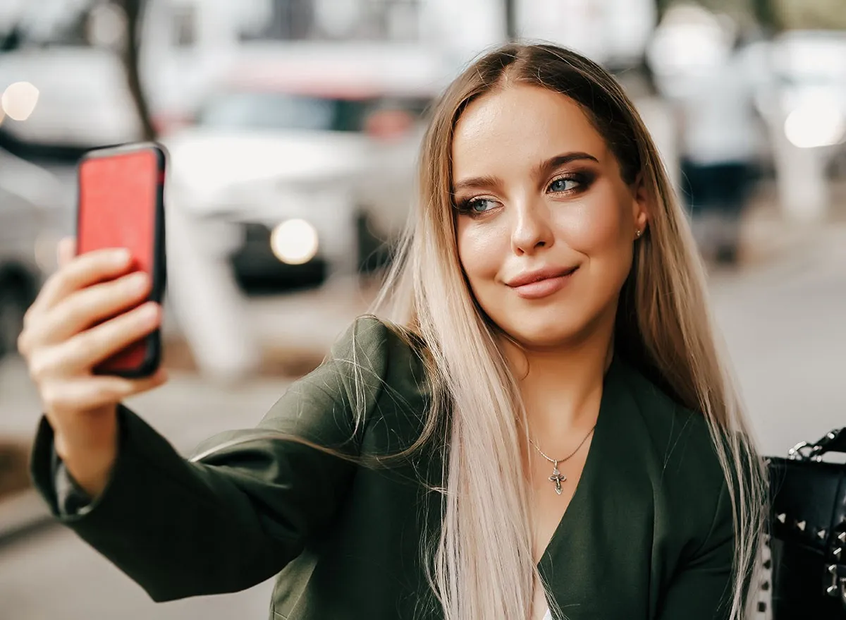 Cute and pretty fashion trendy business woman or girl makes selfie on smartphone camera to share on internet social media iphone, cell phone