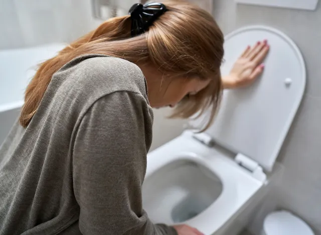Woman bending over toilet and having a nausea, vomit, vomitting, sick, bathroom