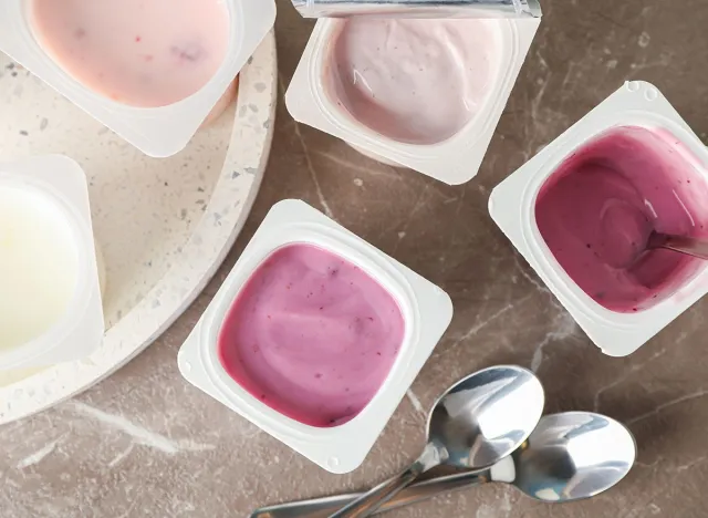 Composition with plastic cups with yogurt on grey table
