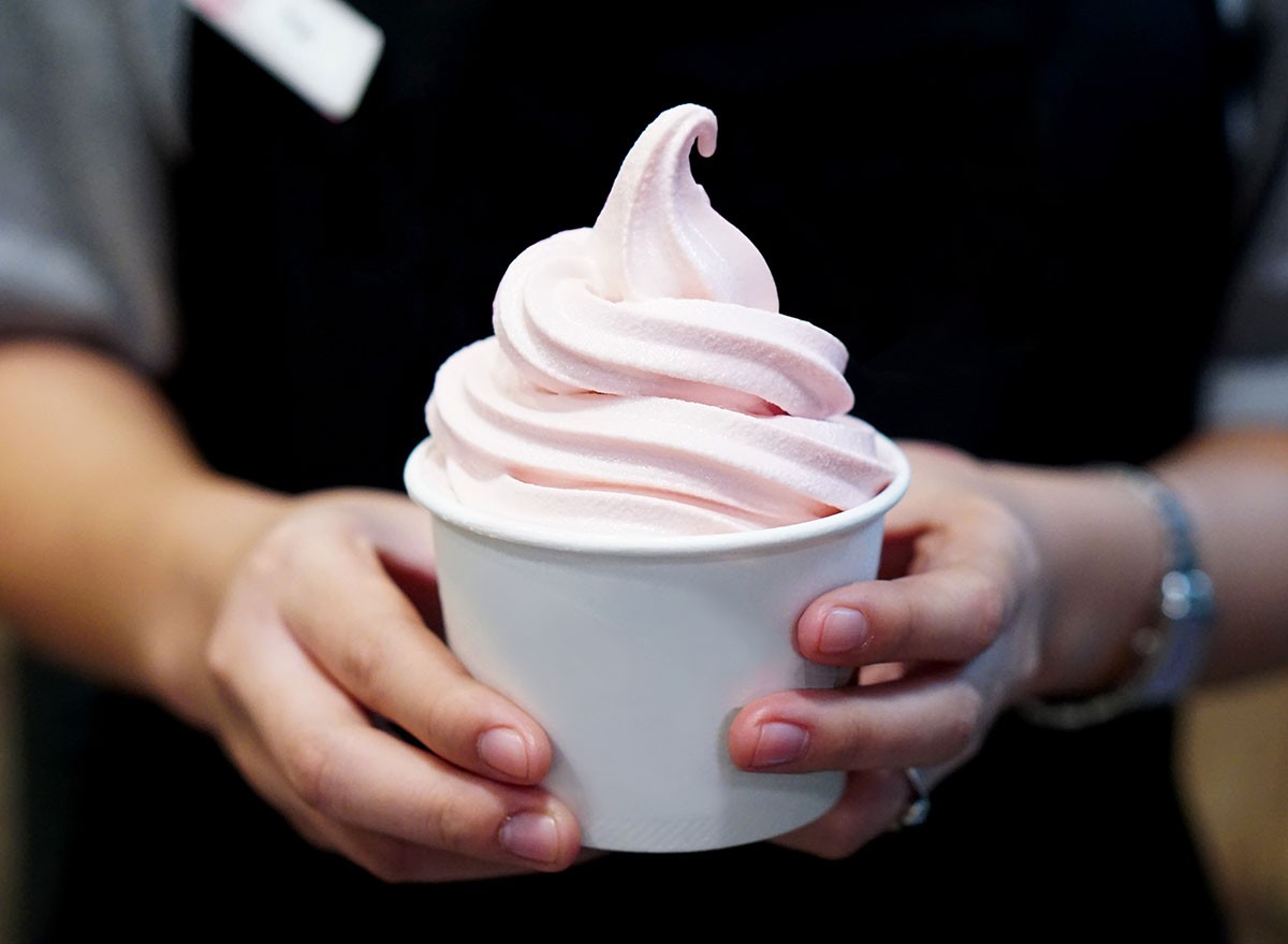 Closeup of woman's hands holding cup with organic frozen yogurt Ice cream served in a plastic takeaway, Healthy eating concept.