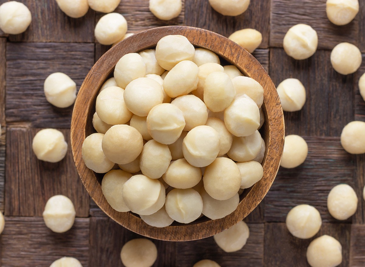 macadamia nuts peeledin bowl on wooden table background.