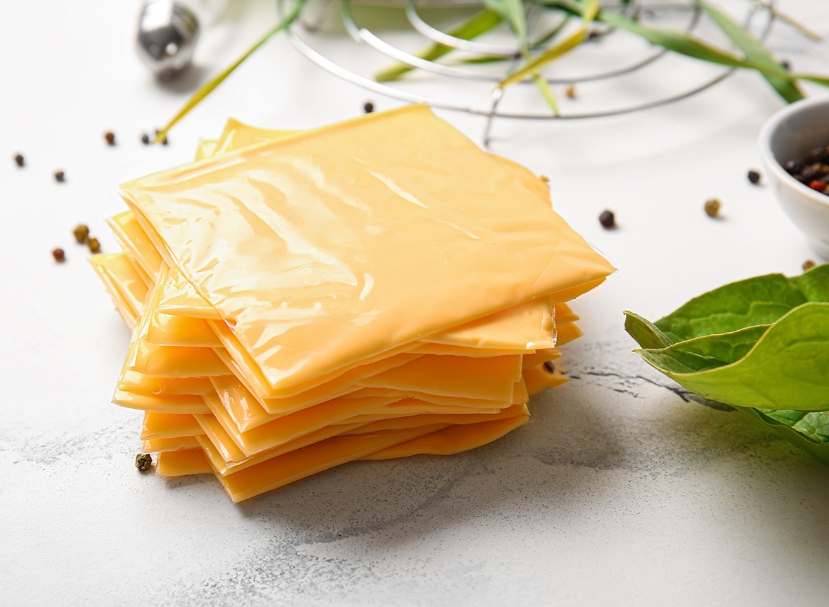 Slices of tasty processed cheese on white marble background