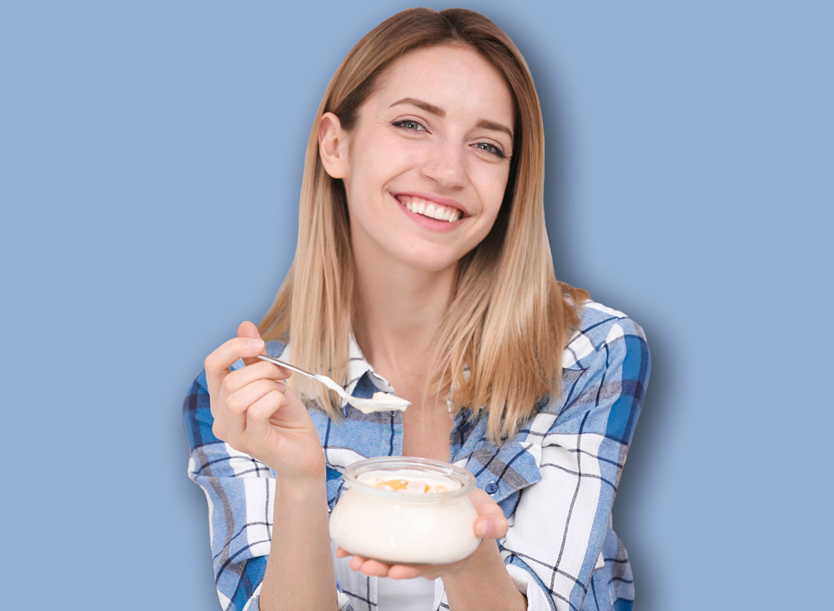 Young attractive woman with tasty yogurt near fridge