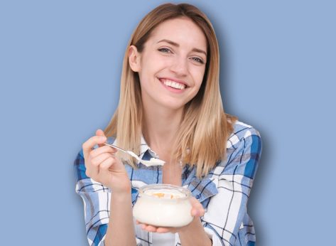 Young attractive woman with tasty yogurt near fridge