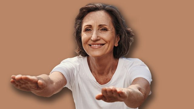 Happy elderly fit woman doing squats outdoors