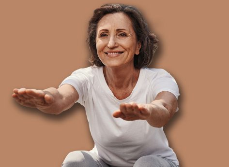 Happy elderly fit woman doing squats outdoors