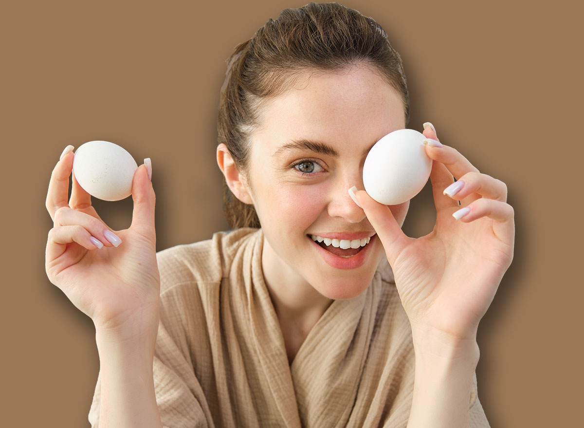 Attractive young cheerful girl baking at the kitchen, making dough, holding recipe book, having ideas.