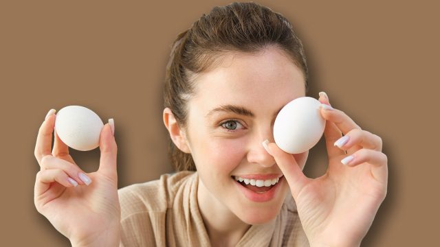 Attractive young cheerful girl baking at the kitchen, making dough, holding recipe book, having ideas.