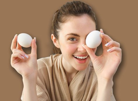 Attractive young cheerful girl baking at the kitchen, making dough, holding recipe book, having ideas.