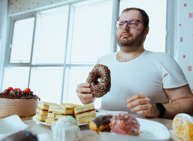 Health problems and extra weight problems because of eating fatty food, fat man with donuts. Unhealthy lifestyle with a high concentration of sugar