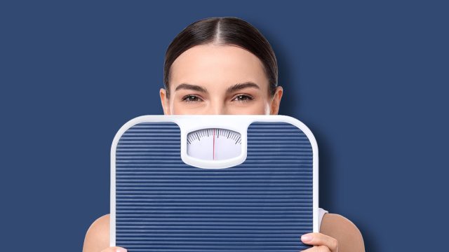 Diet and weight loss concept. Young woman with floor scale on white background