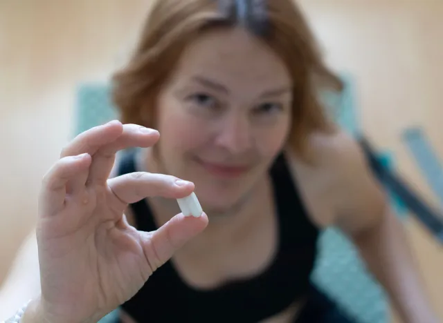 Close-up of a woman holding a white pill, symbolizing oral semaglutide treatment Rybelsus, alternative to Ozempic injections for diabetes and weight management.