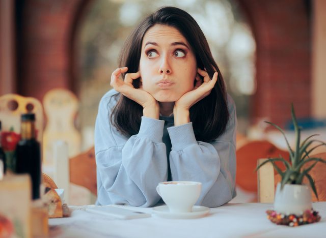 Annoyed Woman Covering Her Ears in Noisy Restaurant. Unhappy cafeteria customer complaining about the environmental noise