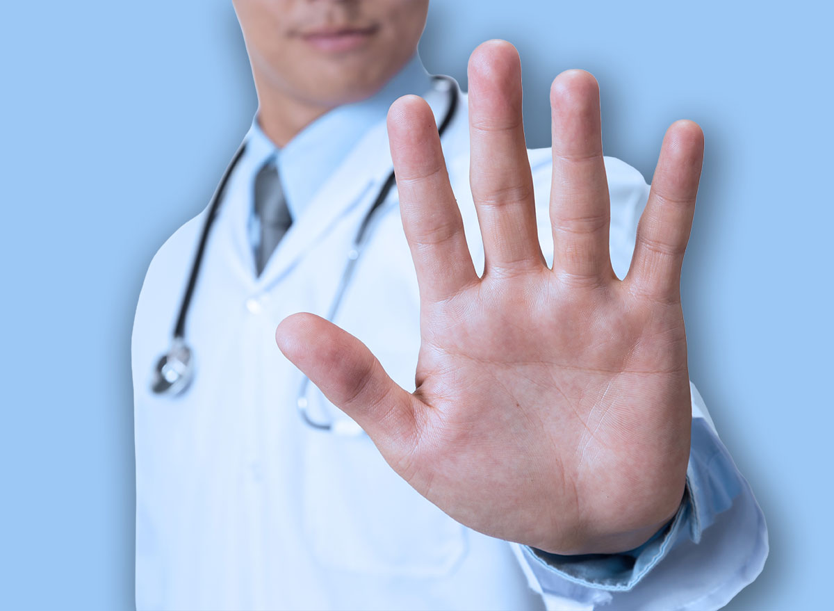 Doctor showing stop sign on white background