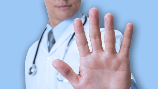 Doctor showing stop sign on white background