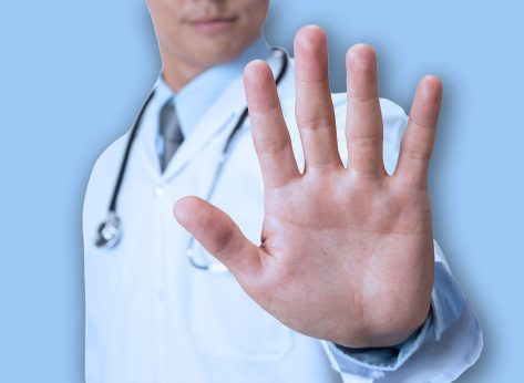 Doctor showing stop sign on white background