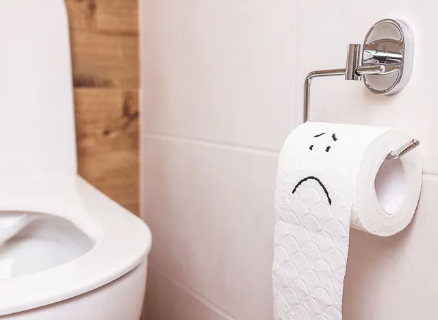 close-up sad emoticon on a roll of toilet paper hanging in the toilet room