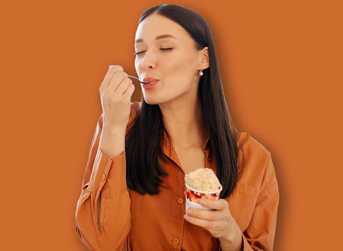 Happy young woman enjoy eating tasty ice cream with closed eyes, sitting in kitchen interior at home, free space