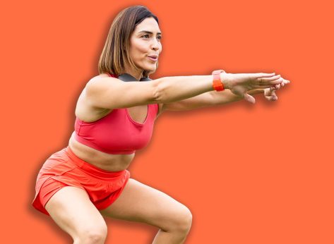 An attractive woman between 30 and 40 years old is doing sports outdoors.The woman is doing a squat to work her legs.Concept of adult women doing sports.