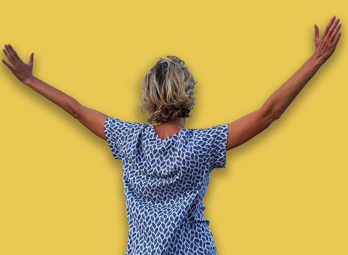 Happy woman enjoying with arms spreaded outdoors, back view