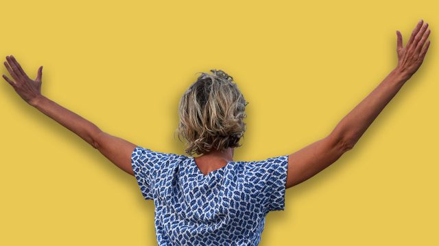 Happy woman enjoying with arms spreaded outdoors, back view