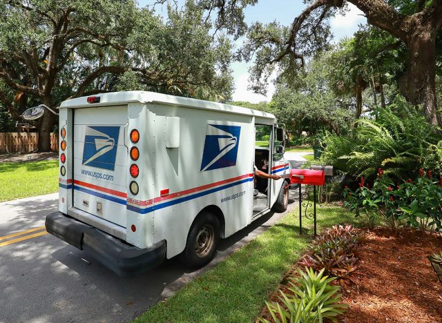 FORT LAUDERDALE, FLORIDA, USA: Mail man delivering mail in a postal truck puts letters into a post mounted red mailbox as seen on September 3, 2020.