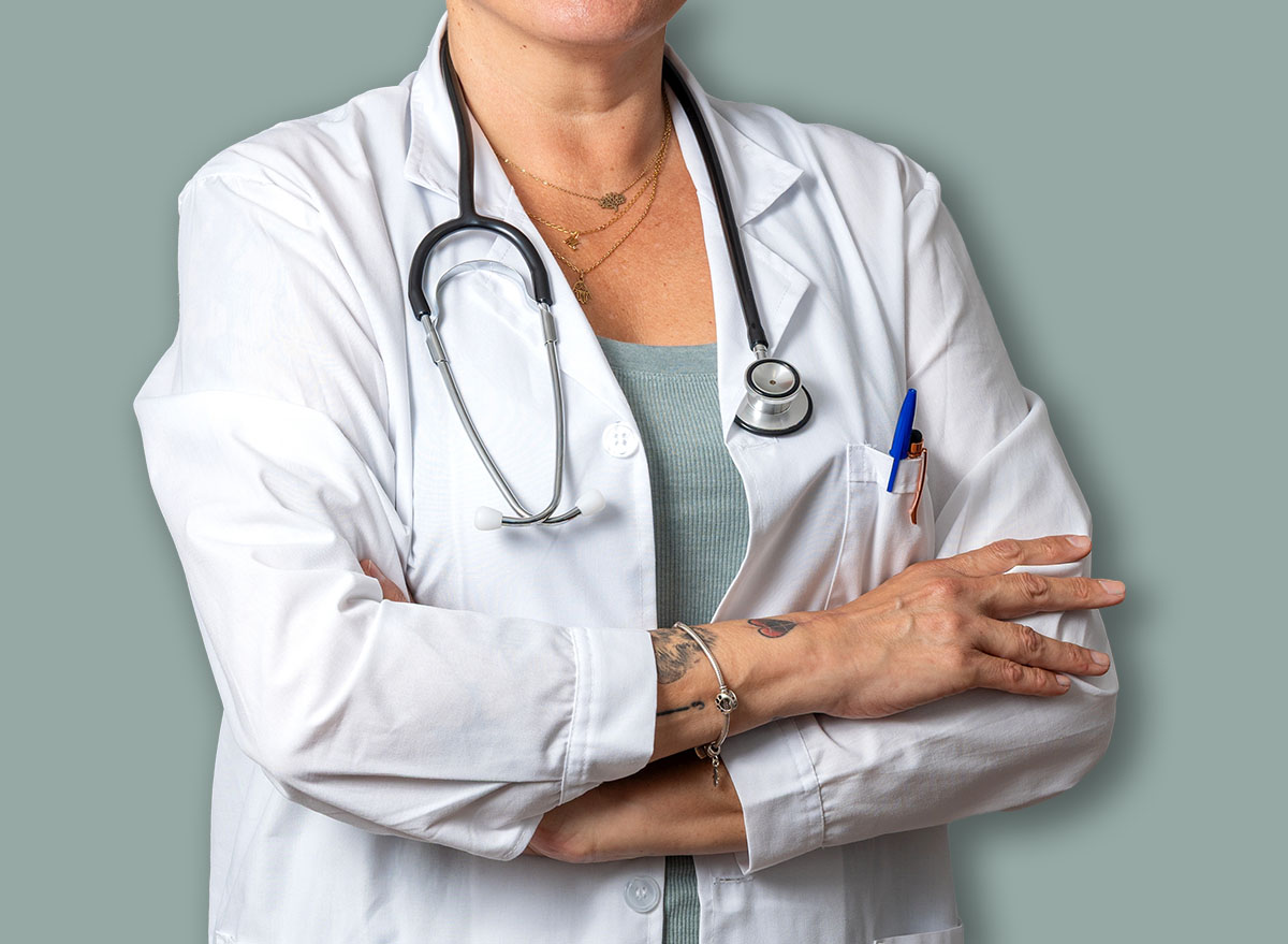 Portrait of a smiling senior female doctor wearing a lab coat and stethoscope, exuding confidence with crossed arms