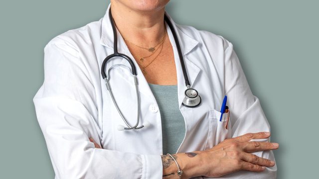 Portrait of a smiling senior female doctor wearing a lab coat and stethoscope, exuding confidence with crossed arms