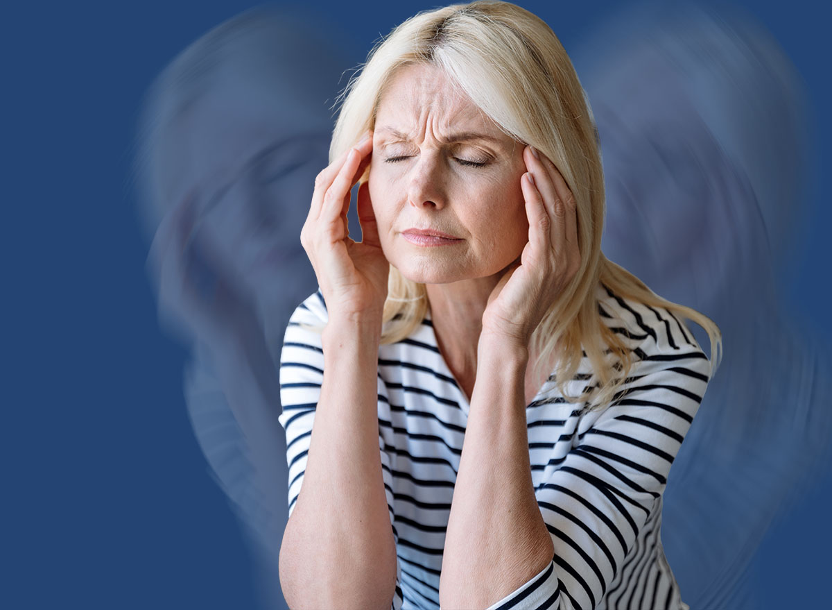 Portrait of mature woman touching, massaging temples and suffering from severe head ache. Problems with memory, disorder. Female sitting on armchair at home