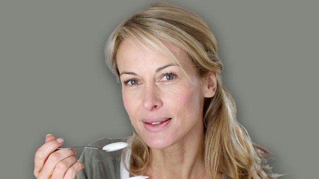 Portrait of middle-aged woman eating yoghurt