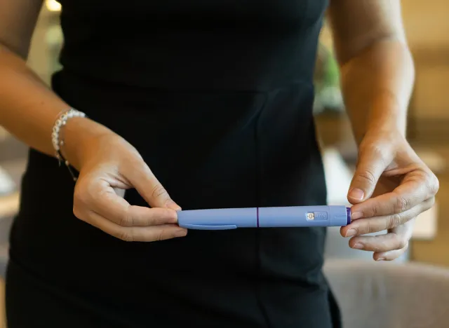 A woman in a black dress holding an ozempic pen, concept of medical treatment, modern healthcare, and weight loss solutions.