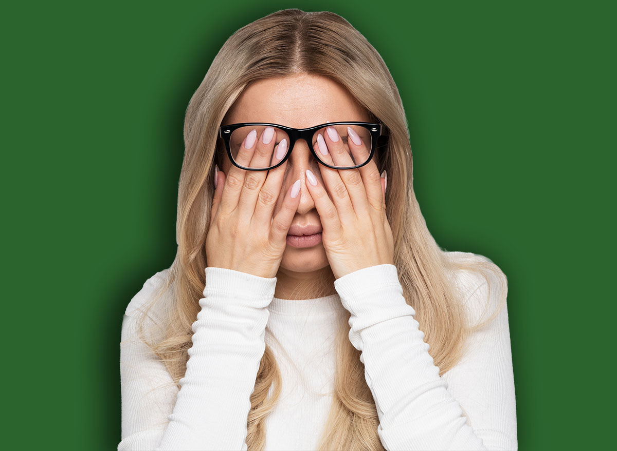 Sleepy young caucasian businesswoman in eyeglasses rubbing her eyes, feels tired after working on laptop, isolated on grey background.Overwork, tired, health concept.Exhausted, fatigue eyes