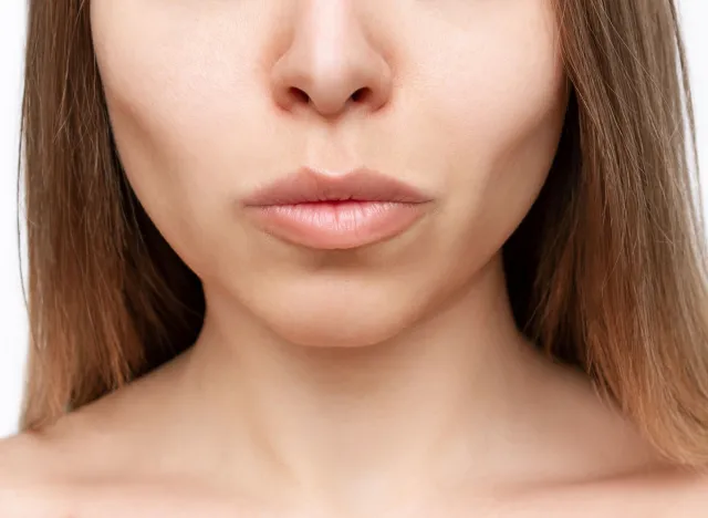 Cropped shot of a young woman's lower part of the face with clear highlighted cheekbones isolated on a white background. Plastic surgery buccal fat removal. Result of cosmetic surgery