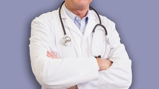 Doctor with arms crossed with colleague behind him in the pharmacy