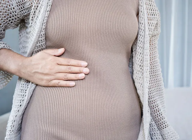 woman holding her right side stomach in pain. Concept of abdominal ache, liver issues, gallstones, or appendicitis.