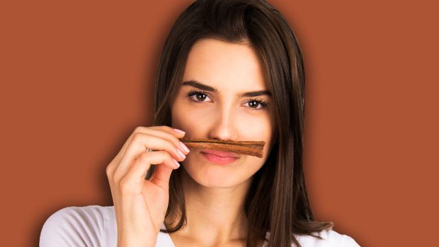 cinnamon concept girl holding and smelling cinnamon stick