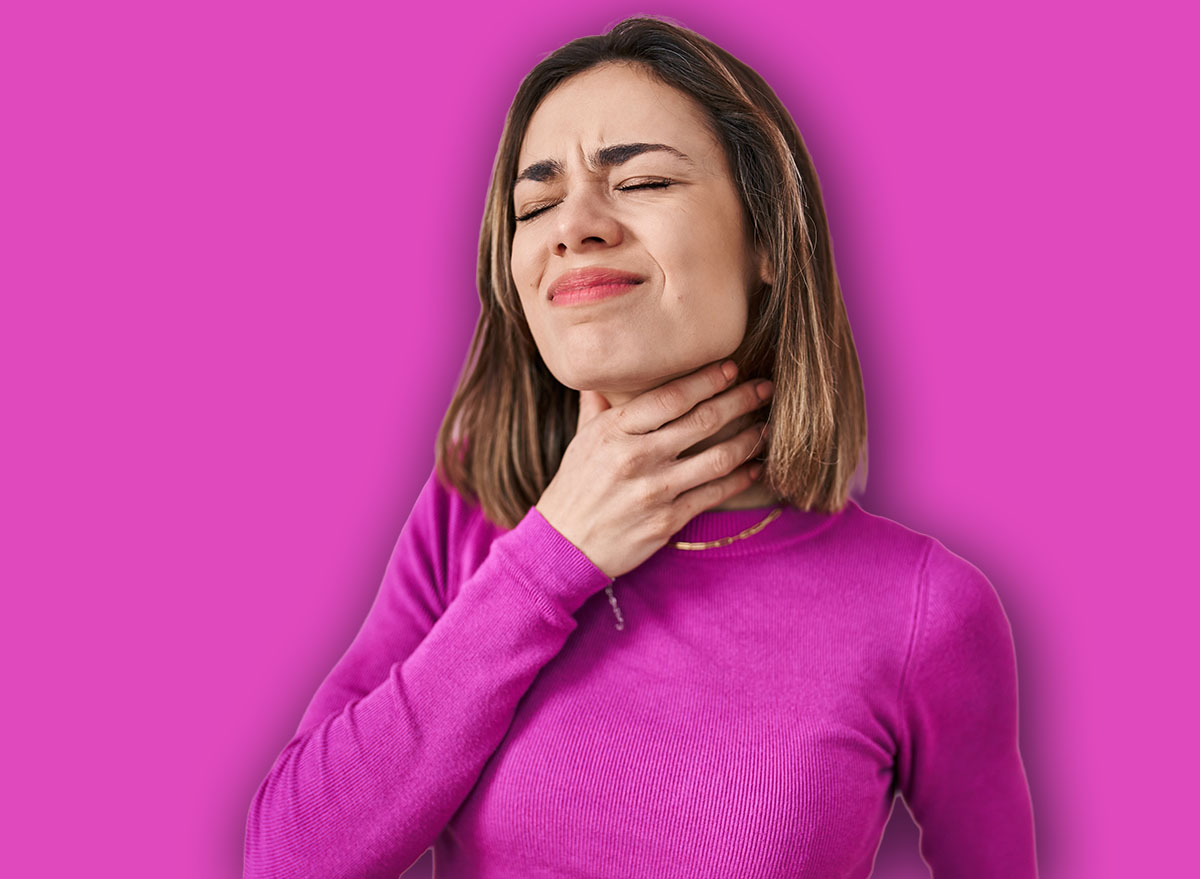 Hispanic woman standing over pink background touching painful neck, sore throat for flu, clod and infection